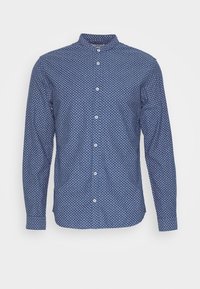 Sininen pitkähihainen nappipusero, jossa on valkoinen pieni kukkakuosi ja kapea kaulus valkoista taustaa vasten.