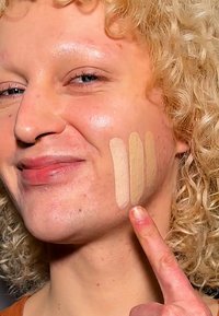 Foundationprøver i fire nyanser påført kinnet; nyansene varierer fra lys beige til litt mørkere beige. Glatt tekstur.