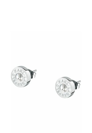 Runde sølv ørestikker med klare centrale krystaller, graveret med "KARL LAGERFELD" rundt kanten, vist på hvid baggrund.