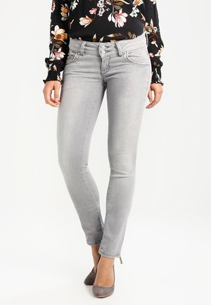 Grijze skinny jeans met een gladde textuur, een middelhoge tailleband en een vijf-pocket ontwerp, aangevuld met een zwart blouse met bloemenpatroon.