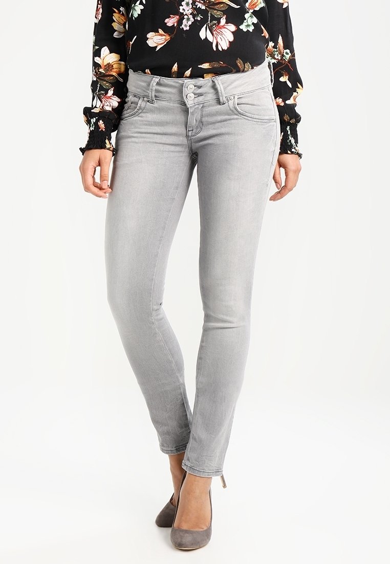 Šedé skinny jeans s hladkým povrchem, středně vysokým pasem a designem s pěti kapsami, doplněné černou blůzkou s květinovým vzorem.