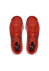 Zapatos deportivos rojos con parte superior de malla texturizada, detalles en negro y suelas blancas. Presentan un diseño con cordones y un logo de Puma en el costado.