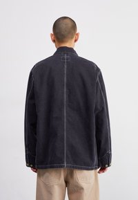 Dark gray denim jacket with a high collar, visible stitching, and snap-button details. Back view shows a clean design and straight cut.