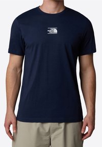 Mörkblå T-shirt med rund halsringning, tillverkad av mjuk bomull, med en liten vit logotyp på bröstet och korta ärmar.