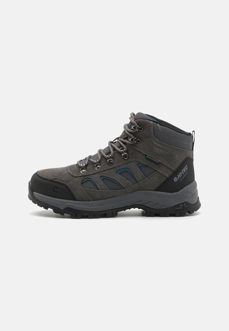 Wanderschuh mit grauem Wildleder- und Mesh-Obermaterial, schwarzem Gummikappen, blauen Akzenten, Metall-Ösen und einer strukturierten schwarzen Sohle für Traktion.
