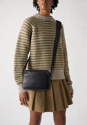 Borsa a tracolla in pelle nera con una texture liscia e design minimalista, caratterizzata da un logo discreto sul davanti e una tracolla regolabile.