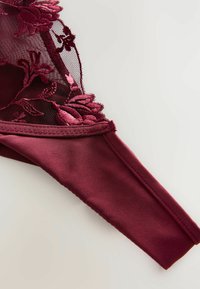 Lenjerie de culoare burgundy, realizată din dantelă florală și material satinat. Designul include broderie texturată și un brâu neted.