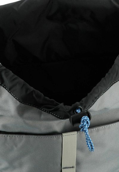 Bolsa de tela gris con interior negro, que presenta un cierre de cordón, cuerda azul y costuras de un gris claro. Textura lisa, forma cilíndrica.
