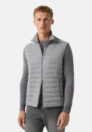 Graue Steppweste mit einem Reißverschluss auf der Vorderseite, hohem Kragen und gestepptem Muster. Weicher Stoff, taillierte Passform und seitliche Taschen. Über einem grauen Sweater getragen.