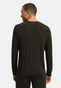 Lange mouw, donkergroen shirt met een ontspannen pasvorm, gladde textuur en ronde kraag. De stof lijkt licht van gewicht en ademend te zijn.