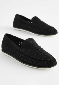 Black suede slip-on shoes featuring an intricate woven design and a contrasting white sole; smooth texture with rounded toe.