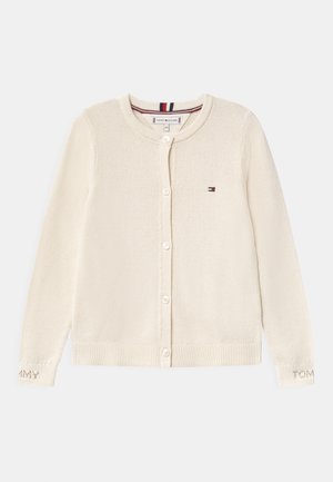 Crème gebreide cardigan met knoopsluiting, ronde hals en geribde manchetten. Voorzien van geborduurd "TOMMY" op de mouw.