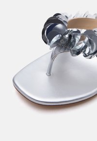 Ασημί σανδάλι με λουράκι, τετράγωνη μύτη και διακοσμητικές επικαλυπτόμενες κυκλικές παγιέτες σε μαύρο και γκρι χρώμα.