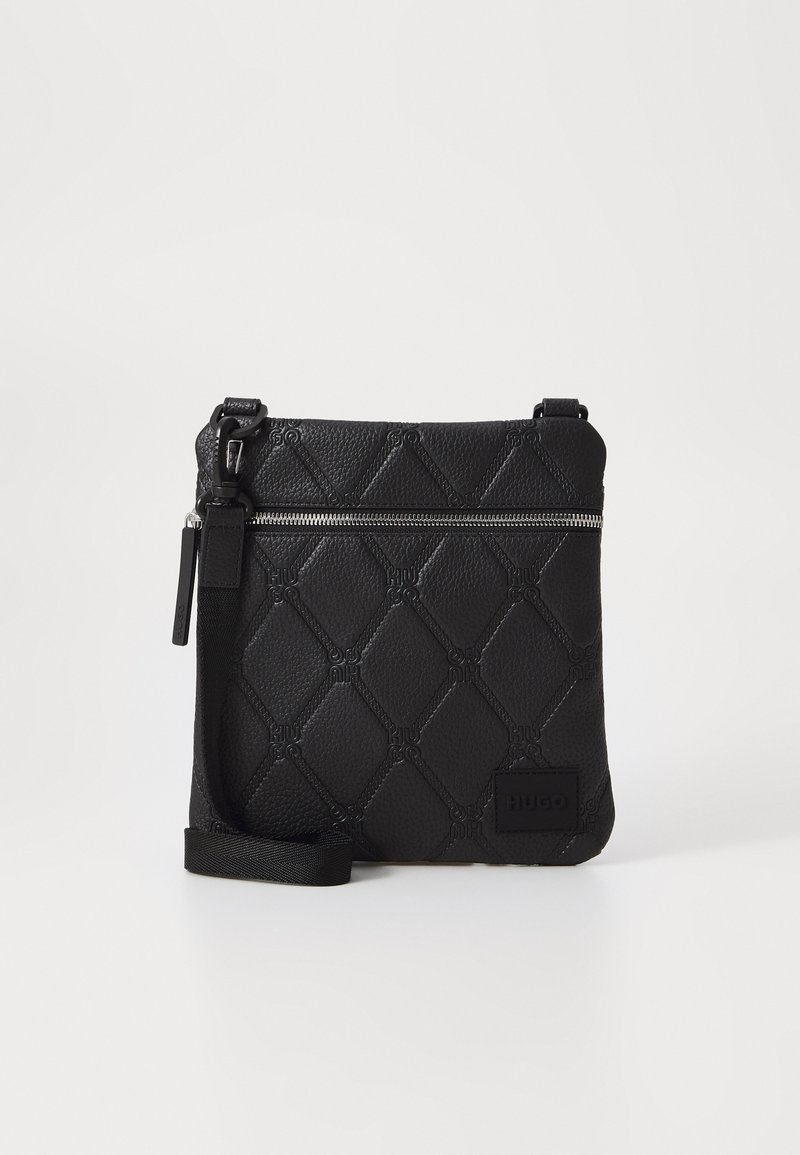 Schwarz strukturierte Leder-Crossbody-Tasche mit einem Rautenmuster, einem silbernen Reißverschluss und einem verstellbaren Tragegurt mit einem Logo-Patch.