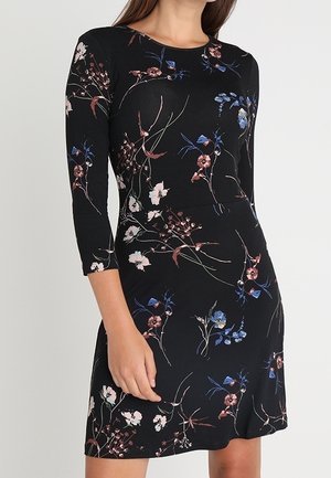 Musta polvimittainen mekko, jossa on kolmen neljäsosan hihat ja herkkä kukkakuosi vaaleanpunaisissa, sinisissä ja valkoisissa sävyissä.
