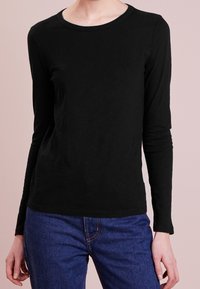 Mustapaita, jossa on pitkät hihat ja pyöreä kaula-aukko, valmistettu pehmeästä kankaasta. Siinä on slim fit -leikkaus, hienovarainen rakenne ja sileä helma.