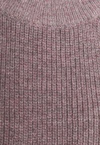 Överdimensionerad ribbstickad tröja i en dämpad mauve färg. Texturerad tyg med vertikala linjer, med hög halsringning och tjockt garn.