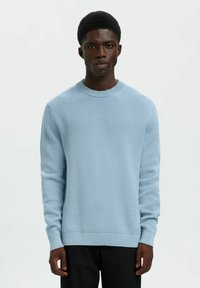 Svijetloplavi pleteni pulover s okruglim izrezom, rebrastim manžetama i rubom. Sadrži teksturirani uzorak i opušteni kroj.