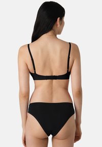 Zwart bikini set met een eenvoudige bralette met verstelbare bandjes en een haaksluiting, gecombineerd met low-rise bikini broekjes. Gladde textuur.