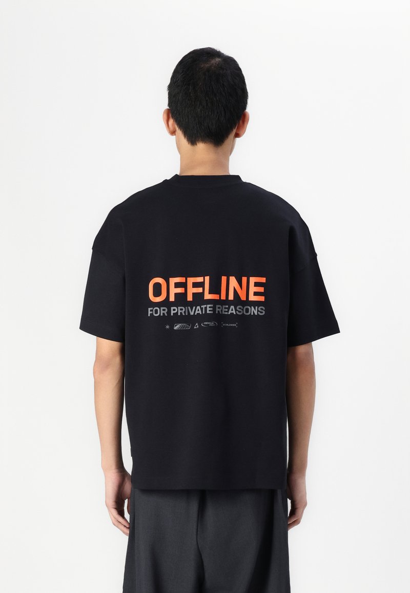 Schwarzes, übergroßes T-Shirt mit orangefarbenem Text auf der Rückseite, der "OFFLINE FOR PRIVATE REASONS" lautet. Aus Baumwolle mit kurzen Ärmeln gefertigt.