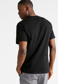 Zwarte korte mouwen t-shirt van katoen, met een ronde hals en een ontspannen pasvorm, met zichtbare stiksels en een zachte textuur.