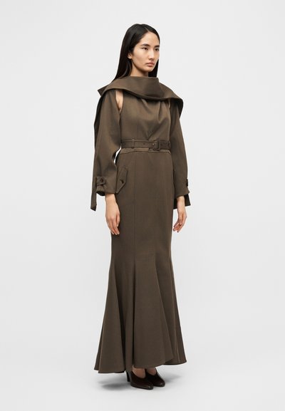 Μακρύ καφέ φόρεμα με εφαρμοστό μπούστο, φαρδύ γιακά και φουσκωτή φούστα. Διαθέτει ζώνη στη μέση και λεπτά μανίκια με κουμπιά.