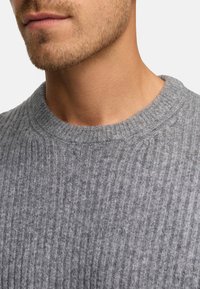 Grå strikket sweater med ribbet tekstur og rund halsudskæring. Stoffet ser blødt ud med en subtil glans.