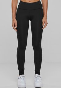 Leggings sportivi neri con una vita alta e senza cuciture. Tessuto morbido e elastico, design aderente che si estende fino alle caviglie.