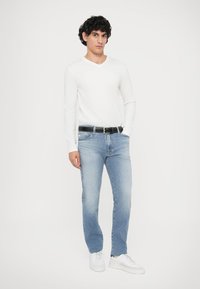 Λευκό πουκάμισο με μακριά μανίκια, ανοιχτό μπλε τζιν, μαύρη ζώνη και λευκά αθλητικά παπούτσια. Λείο ύφασμα, κανονική εφαρμογή, κλασικό σχέδιο, ελάχιστες λεπτομέρειες.