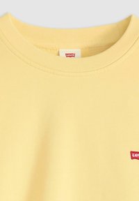 Lichtgele sweatshirt met ronde hals en ribbelkraag, met klein rood Levi's logo op de borst.