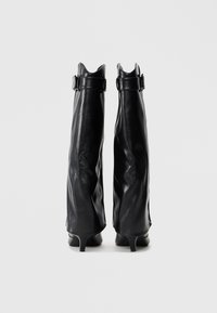Stivaletti neri in pelle con un design arricciato, punta appuntita e cinturini con fibbia nella parte superiore. Texture liscia con una finitura lucida.