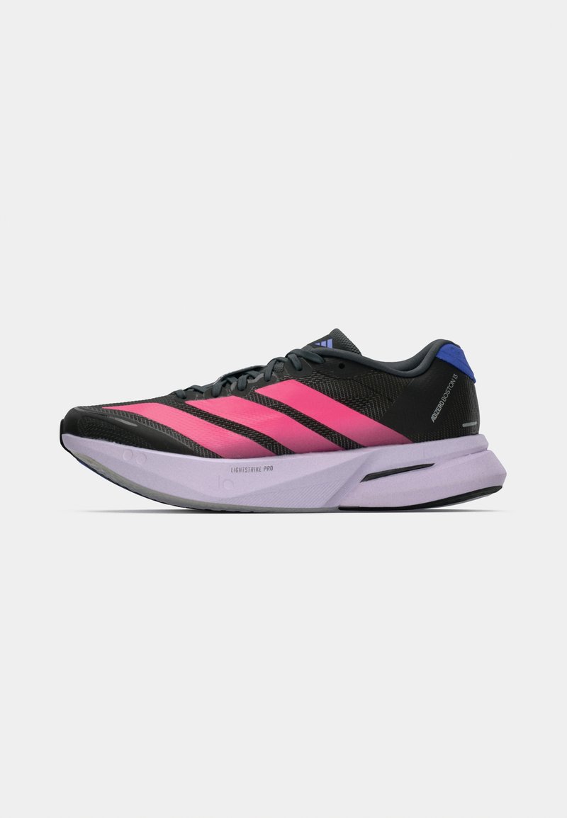 Μαύρο και ροζ τρέχον παπούτσι Adidas με μωβ σόλα, μαύρα κορδόνια και μπλε ταμπελάκι στη φτέρνα, εμφανιζόμενο σε πλάγια όψη σε λευκό φόντο.