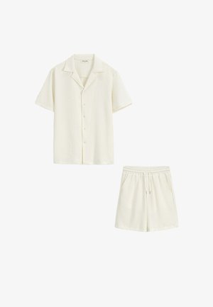 Chemise crème à manches courtes boutonnée et shorts assortis à taille élastique avec un motif texturé subtil sur fond blanc.