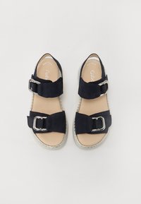 Navy suede sandals featuring two wide straps with large silver buckles and a light-colored textured sole. Natural-tone insole with printed branding.