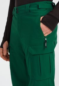Groene cargo broek van duurzaam materiaal, met zijzakken, een ritszak en een verstelbare tailleband met een gladde textuur.