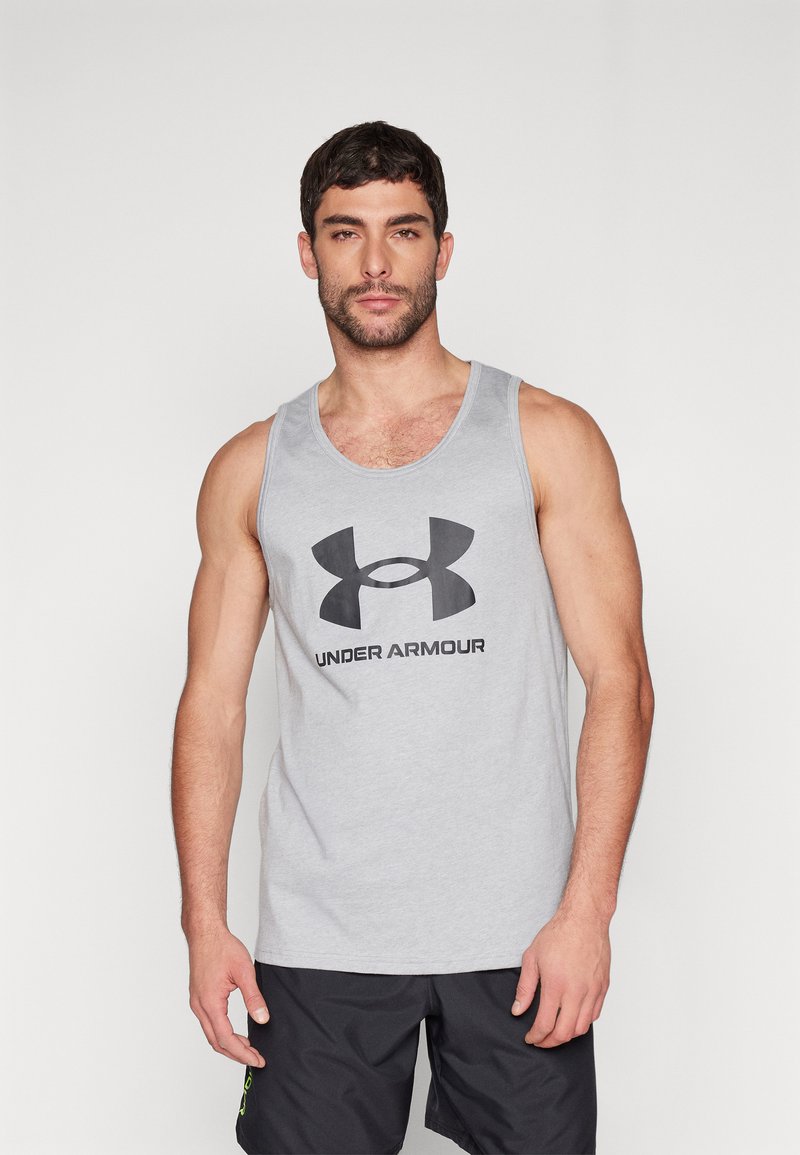 Szürke pamut trikó, amelynek elülső részén egy nagy fekete Under Armour logó található, lekerekített nyakkal és széles karöltőkkel.