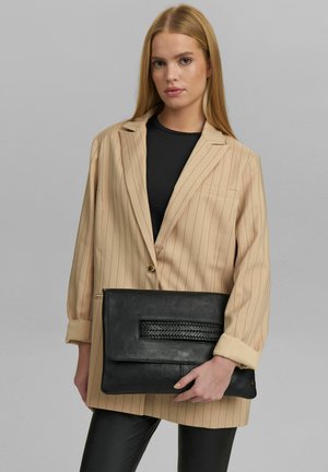 Beige randig blazer med långa ärmar, i kombination med en svart läderkuvertväska med vävd detalj. Outfiten kontrasterar texturer och färger.