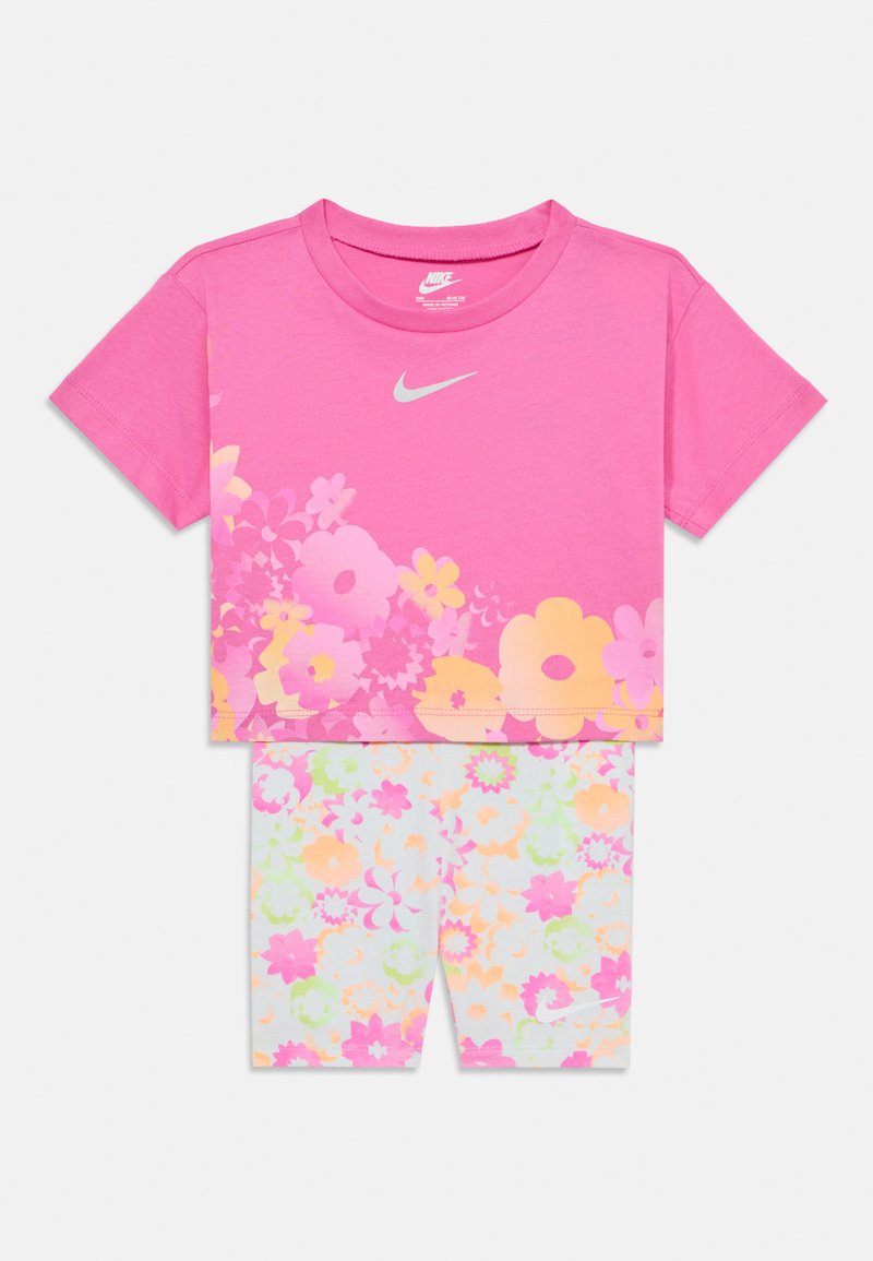 Paita lyhyillä hihoilla, jossa on pinkki kukkakuosi, pyöreä pääntie ja harmaa logo, yhdistettynä vastaaviin joustaviin shortseihin, joissa on värikkäitä kukkakuosia.