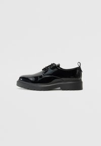 Chaussures en cuir verni noir avec un bout arrondi, un design à lacets et une semelle en caoutchouc épaisse. Elles sont dotées d'une languette à l'arrière pour faciliter l'enfilage.