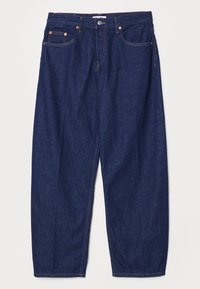 Tmavě modré džínové kalhoty s volným střihem, pěti kapsami a měděnou kovovou výbavou. Viditelné švy zdůrazňují design.