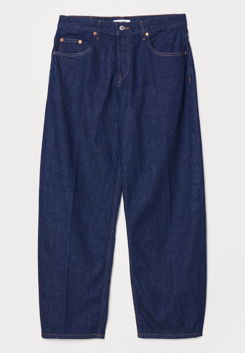 Tmavě modré džínové kalhoty s volným střihem, pěti kapsami a měděnou kovovou výbavou. Viditelné švy zdůrazňují design.