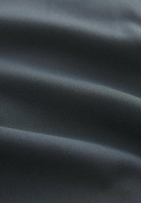 Tejido gris oscuro con una textura suave y un sutil patrón de canalé, que muestra suaves pliegues y una caída ligera.