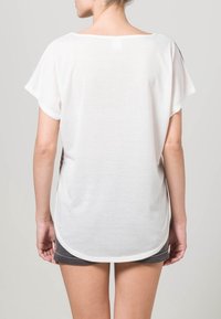 Bílá tričko s krátkým rukávem a volným střihem, s oblým lemem a měkkým, lehkým materiálem. Žádné viditelné vzory nebo ozdoby.