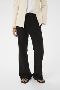 Schwarze, maßgeschneiderte Hose mit lockerem Schnitt, kombiniert mit einem cremefarbenen, strukturierten Blazer mit ausgefransten Kanten und einem einzelknopfverschluss.