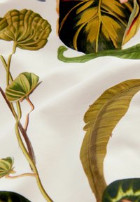 Stoff mit detaillierten botanischen Illustrationen in Grün und Braun auf weißem Hintergrund, mit glänzenden Texturen und unterschiedlichen Blattformen.