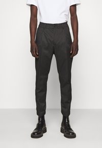 Svarta skräddarsydda byxor med randig mönster, avsmalnande ben, slät front och bälteshällor, ihopparade med svarta läder stövletter.