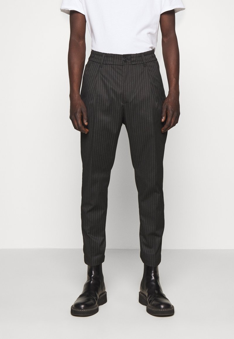 Svarta skräddarsydda byxor med randig mönster, avsmalnande ben, slät front och bälteshällor, ihopparade med svarta läder stövletter.