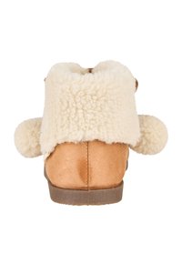 Tan-farbene Wildleder-Ankle-Boots mit einem flauschigen cremefarbenen Schaffellkragen und Pompon-Akzenten, ausgestattet mit einer flachen Gummisohle und genähten Details.