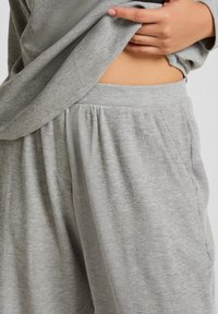 Grå loungewear-set i våffelstickning med en lös topp och byxor med resårmidja, med subtil textur och sidofickor.