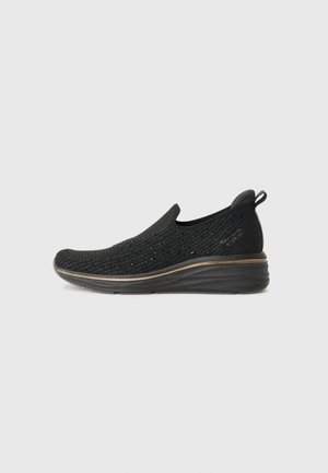 Black slip-on shoes with a textured knit upper, a rounded toe, and a cushioned sole. Features a subtle contrasting gold trim along the base.